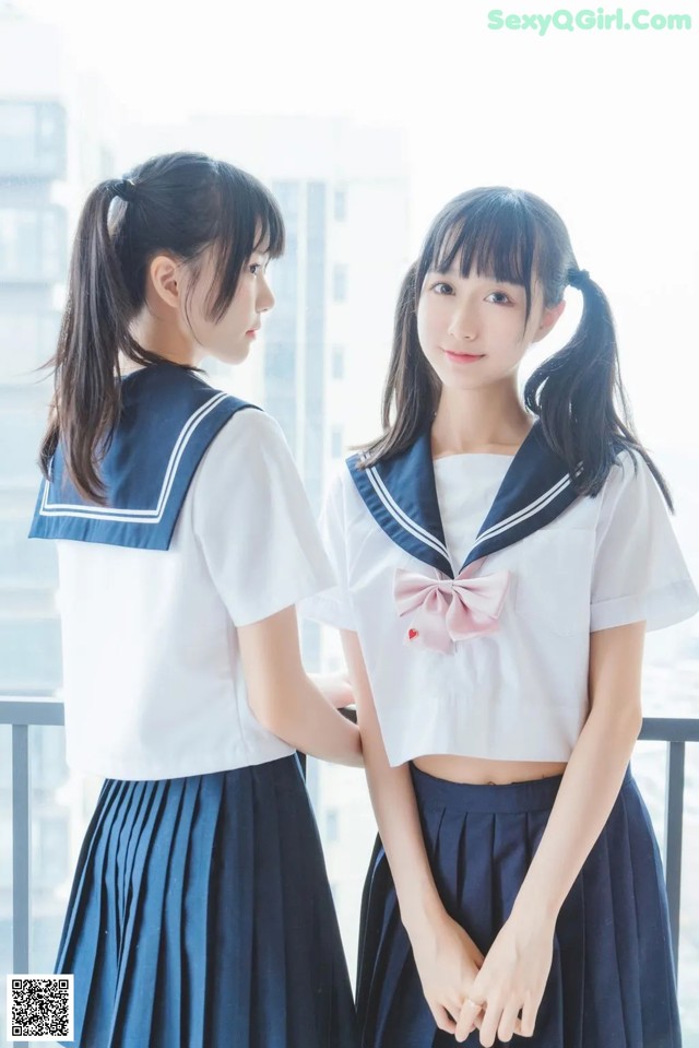 Two young women in school uniforms standing next to each other.