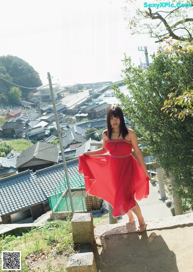 A woman in a red dress standing on a stone wall.