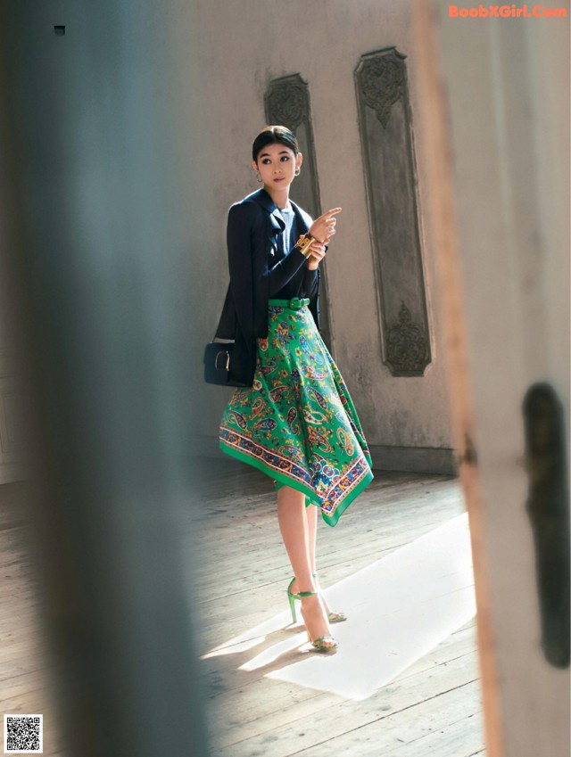 A woman in a green skirt and a black blazer.