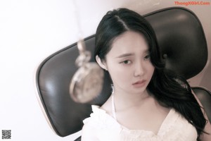 A woman in a white lingerie sitting on a chair.