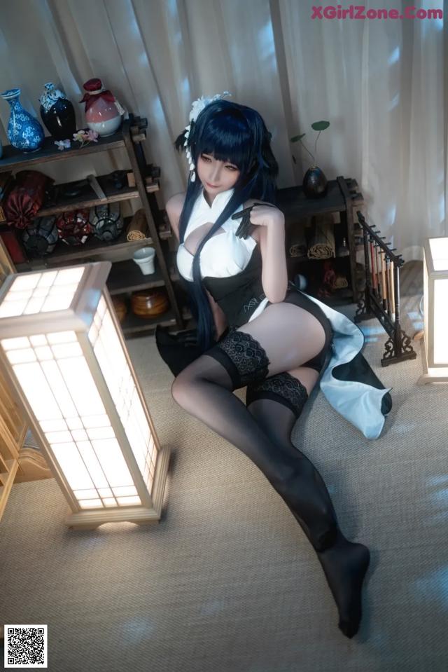 A woman in a black and white outfit sitting on the floor.