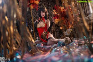 A woman in a red and gold outfit sitting on a rock.