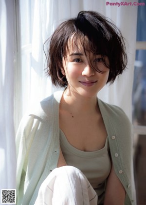A woman in a white dress sitting on a wooden floor.