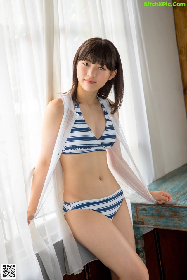 A woman in a blue and white striped bikini posing for a picture.