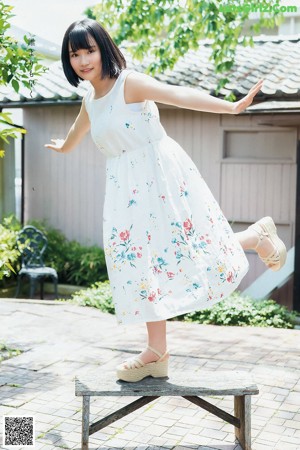 A woman in a white tank top is posing for a picture.