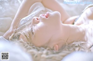 A woman in a white lingerie sitting on a bed.