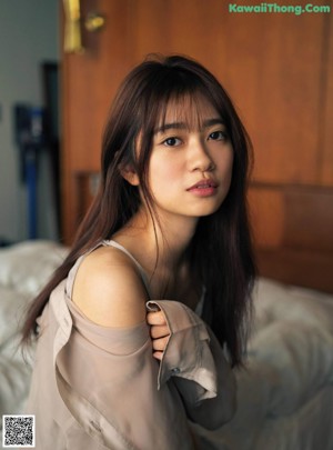 A woman in a yellow sweater and blue shorts posing for a picture.