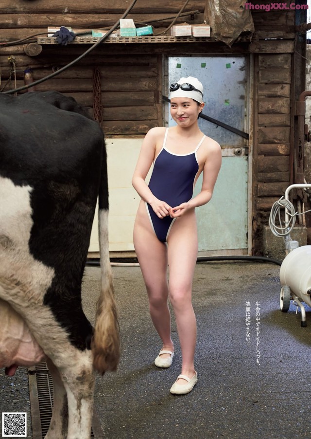 A woman in a bathing suit standing next to a cow.