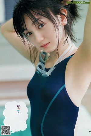 A woman in a bathing suit standing next to a swimming pool.