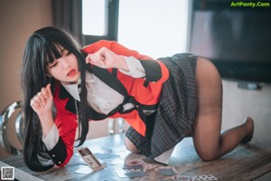 A woman in a red jacket and black stockings sitting on a bed.