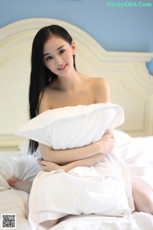 A woman laying on top of a bed covered in white sheets.