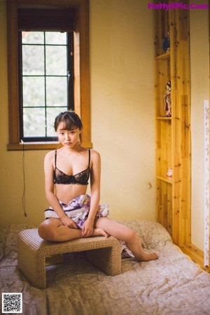 A woman in a black bra and panties holding a bouquet of flowers.