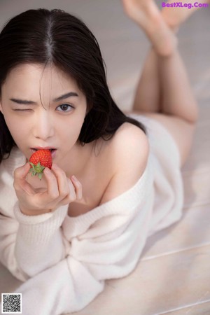 A woman in a white sweater sitting on a white couch.