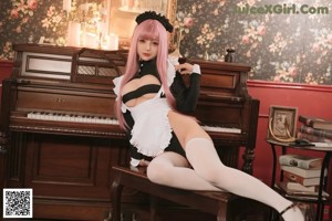 A woman with pink hair sitting on a piano.