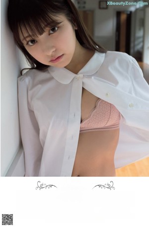 A woman in a white lingerie standing by a window.