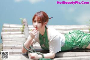 A woman in a green dress sitting on a window sill.