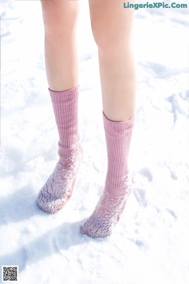 A close up of a person wearing pink socks in the snow.