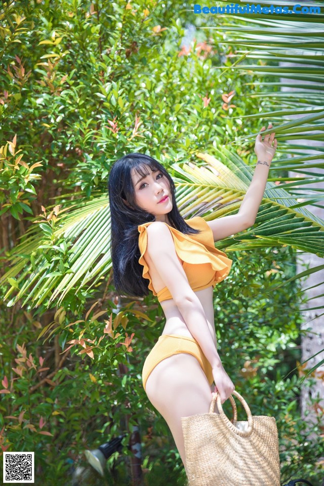 A woman in a yellow bikini posing for a picture.