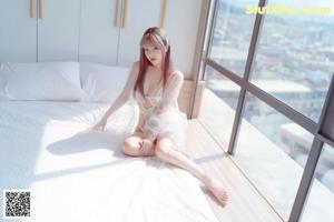 A woman in a white lingerie sitting on a window sill.