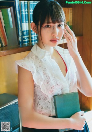 A woman in a red lingerie sitting on a couch reading a book.