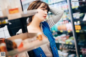 A woman in a blue vest is holding a box of pills.