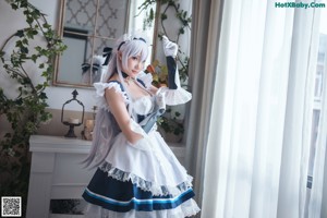 A woman in a maid outfit sitting on the floor.