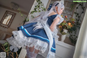 A woman in a maid outfit sitting on a chair.