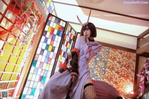 A woman in a kimono holding a red umbrella and a bottle of wine.