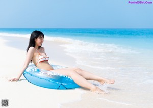 A woman in a yellow and white bathing suit posing for a picture.