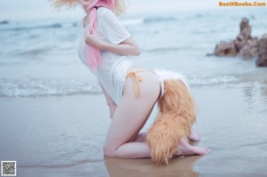 A woman in a bikini and a cat hat on the beach.