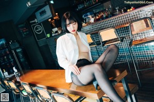 A woman sitting at a bar in a restaurant.
