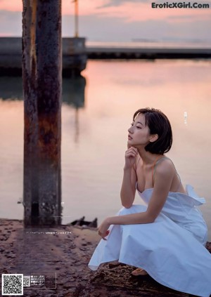 A woman in a white shirt and blue bra top posing for a picture.