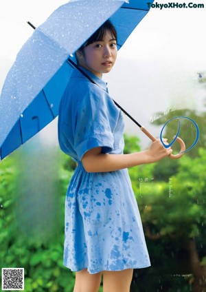 A woman in a blue dress standing in the rain.