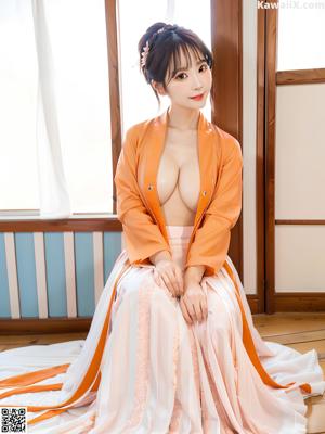 A woman in a purple kimono sitting on a bed.