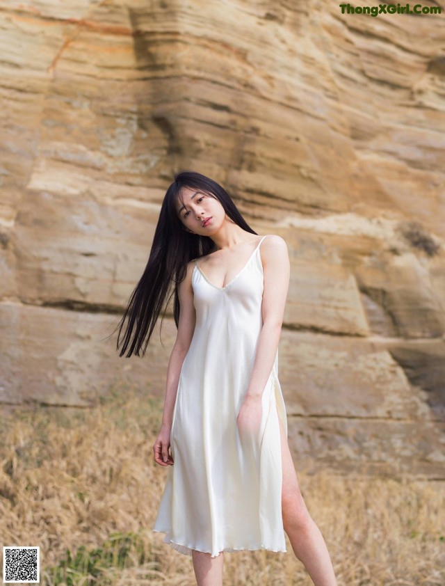 A woman in a white dress standing in a field.